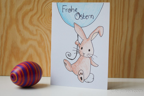 Osterkarte mit einem Osterhasen, der an einem Luftballon hängt