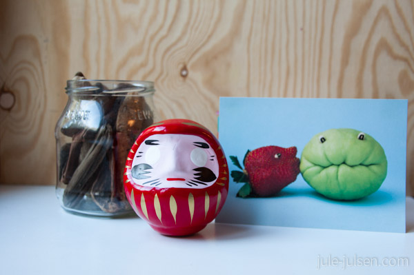 glas mit Treibholz, roter Daruma aus Japan, Karte mit lustigen Früchten glas mit Treibholz, roter Daruma aus Japan, Karte mit lustigen Früchten