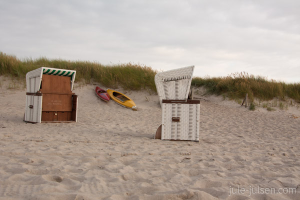 weiße Strandkörbe und Paddelboote am Strand weiße Strandkörbe und Paddelboote am Strand