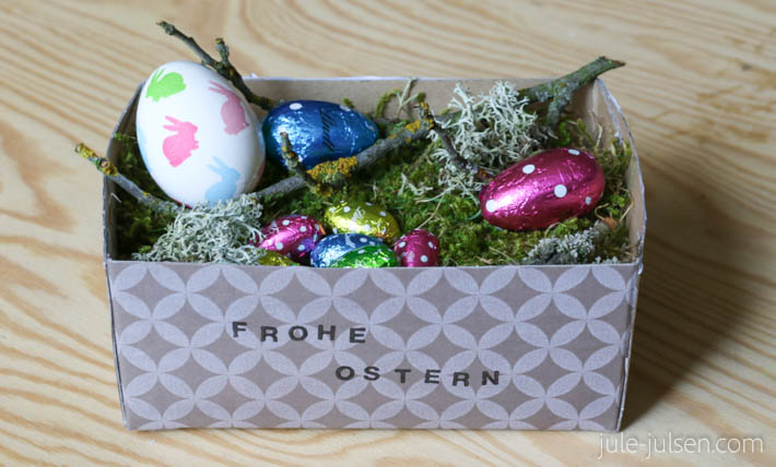 Osterkoerbchen aus Karton und Moos mit bunten Schokoeiern Osterkoerbchen aus Karton und Moos mit bunten Schokoeiern